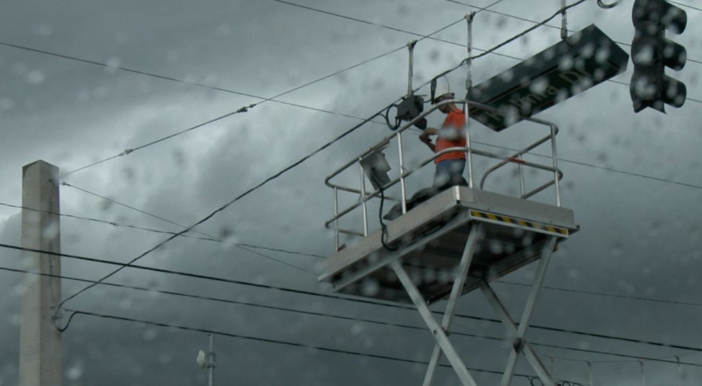 linemen working on a traffic light during rain
